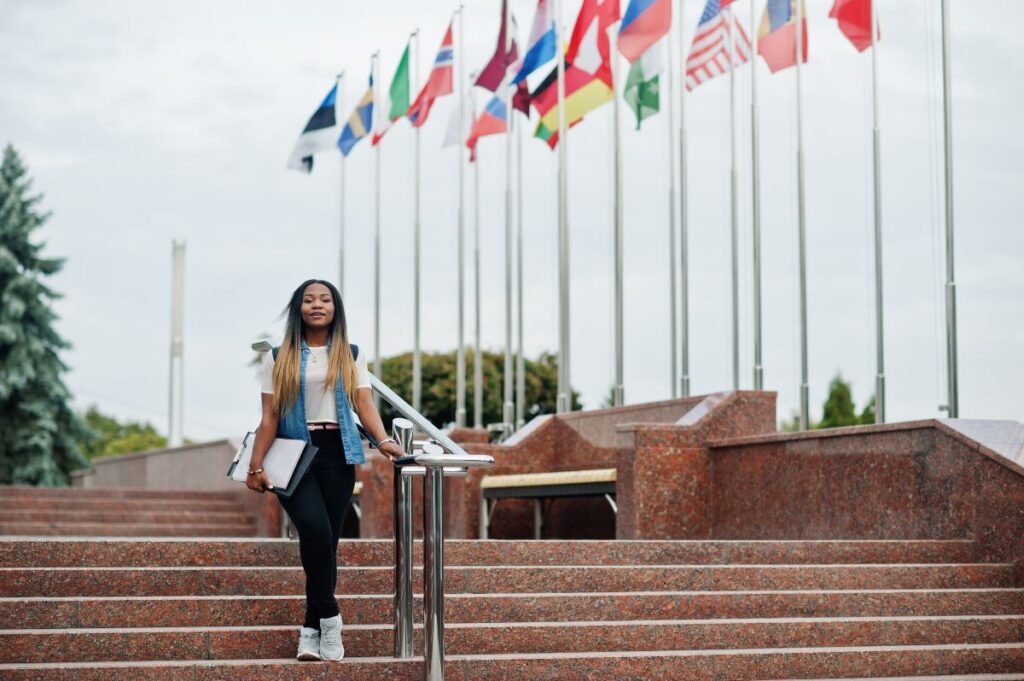 african student female posed with backpack school items yard university against flags different countries copy